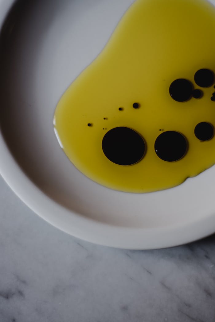 Artistic close-up of olive oil and balsamic vinegar on a white plate, perfect for culinary themes.